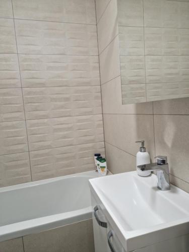 een witte badkamer met een wastafel en een bad bij VICTORY APARTMENT in Subotica