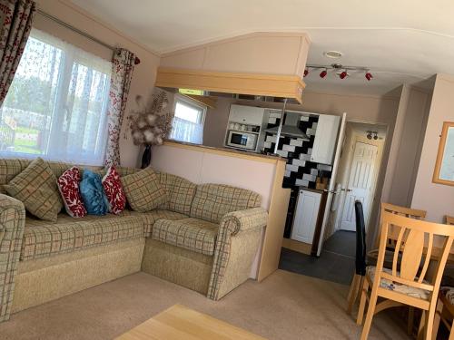 a living room with a couch and a kitchen at MILLFIELDS AT INGOLDMELLS, Skegness in Tattershall
