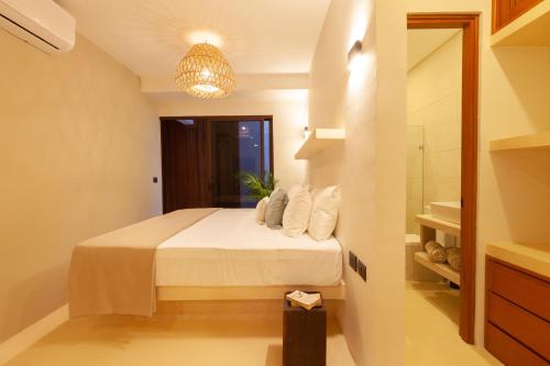 a bedroom with a bed with white sheets and a chandelier at Aparthotel Onda Maya - Adults Only in Holbox Island