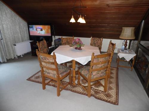 a dining room table and chairs with a white table and a television at Pension C Blickfeld in Winsen