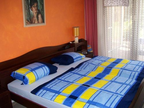 a blue and yellow bed with two blue and yellow pillows at Pension C Blickfeld in Winsen Aller