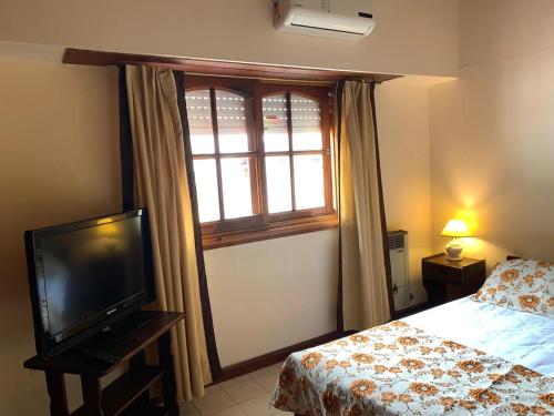 ein Schlafzimmer mit einem Bett, einem Fernseher und einem Fenster in der Unterkunft Casa Elena in Villa Gesell