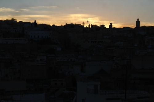 a city skyline with the sun setting in the background at Riad Fes Elite in Fès