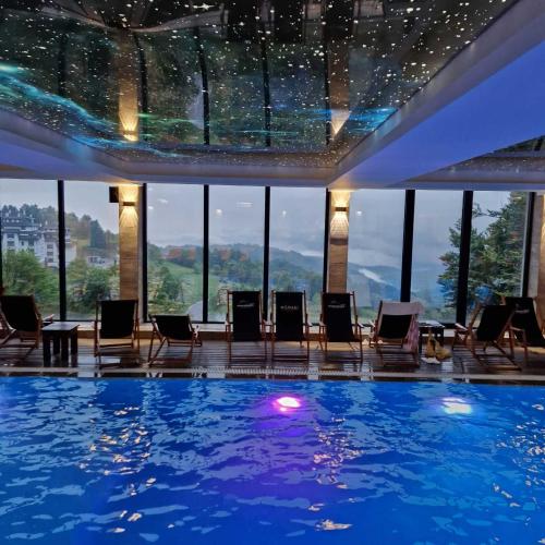 a pool in a hotel with chairs and a view at Lola apartman Milmari & Residence Hill in Kopaonik