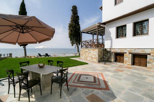 a patio with a table and chairs and an umbrella at Mermaid Villa & Apartment Common Areas in Koropi