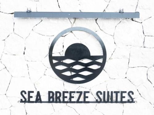 a sign that says sea breeze suites on a stone wall at Sea breeze suites Mistral 4 per with private pool in Kandia