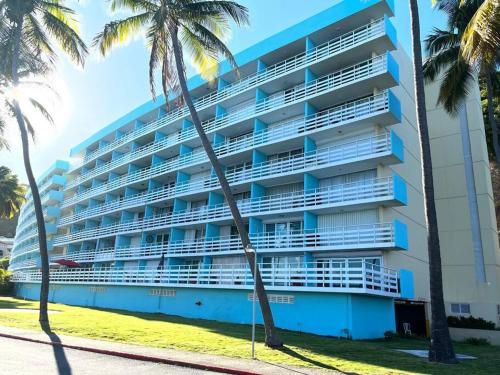 a large building with palm trees in front of it at Hermoso Estudio frente al mar Ocean Blue Faith in Fajardo