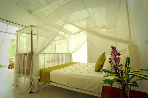 a bedroom with a canopy bed with a window at Beach Grove Villas in Unawatuna