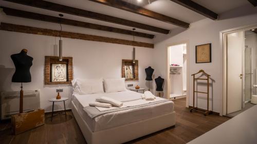 een witte slaapkamer met een bed en enkele mannequins bij Archhouse in Kalabaka