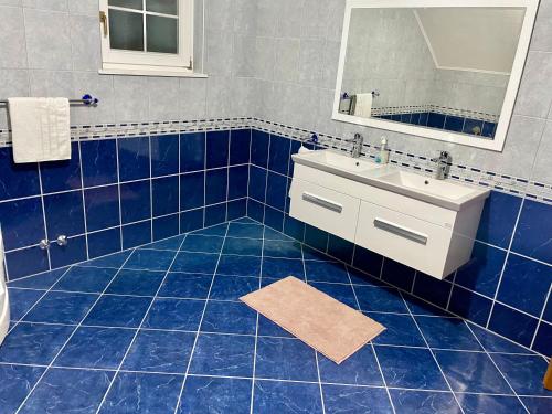 a blue tiled bathroom with a sink and a mirror at Villa Tesla S in Velika Kladuša