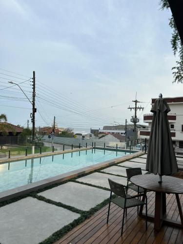 - une terrasse avec une table et un parasol à côté de la piscine dans l'établissement Apto Novo Studio Nature a 50 m da praia, à Torres