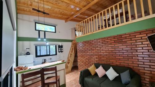 sala de estar con sofá y pared de ladrillo en Minicasa Rural Maria Preta en Puerto Iguazú