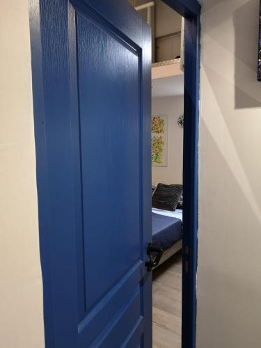 eine blaue Tür, die in ein Zimmer mit einem Bett führt in der Unterkunft Appart VH - Bienvenue au Lilas in Les Lilas