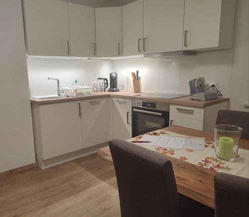 a kitchen with white cabinets and a wooden table at Ferienwohnung Großalber in Maria Neustift