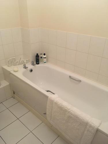 a white bath tub in a bathroom with white tiles at Lovely Two bed flat located in the heart of Dunstable in Dunstable