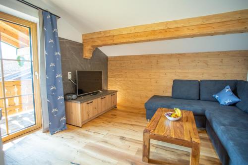 a living room with a blue couch and a table at Ramslerhof - Chiemgau Karte in Inzell
