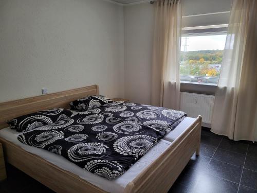 een slaapkamer met een bed met een zwart-witte deken bij schöne, modernisierte Wohnung - Dudweiler in Saarbrücken