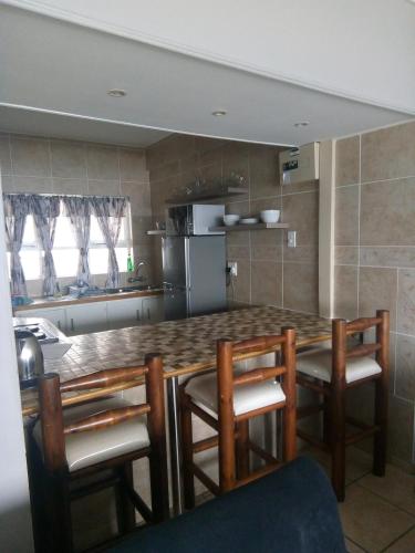 a kitchen with a table with chairs and a refrigerator at Afsaal Holiday Flats in Amanzimtoti