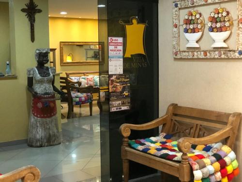 a room with a woman statue and a chair in a store at Hotel Villa de Minas in Monte Sião