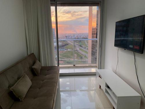 a living room with a couch and a large window at O melhor apartamento no shopping in Águas Claras