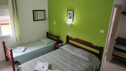 two beds in a room with green walls at HOTEL SÃO NICOLAU in Ubatuba