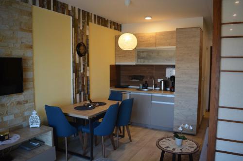 a kitchen with a wooden table and blue chairs at Lola apartman Milmari & Residence Hill in Kopaonik