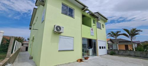 Camelo locação de Suítes Individuais Pousada com Cozinha e Sala Compartilhada في أرويو دو سيلفا: عماره خضراء فيها كلب جالس خارجها