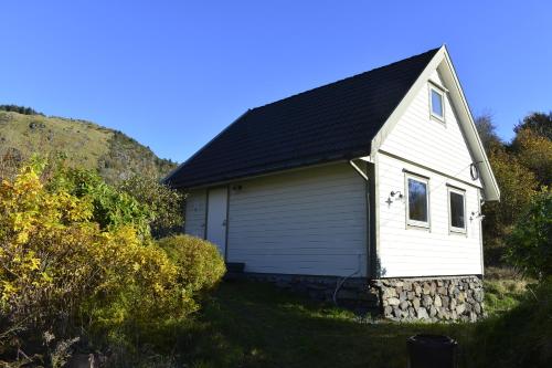 a small white house with a black roof at Guesthouse in Manger, Radøy Island in Kollstad