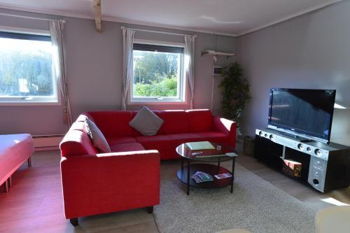 ein Wohnzimmer mit einem roten Sofa und einem Flachbild-TV in der Unterkunft Guesthouse in Manger, Radøy Island in Kollstad