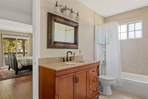 a bathroom with a sink and a toilet and a mirror at Charming Getaway Cabin in Lake Arrowhead