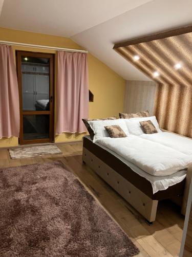 a bedroom with a large bed and a window at Casa Odihnei Villa & Tiny-House in Tîrnăveni