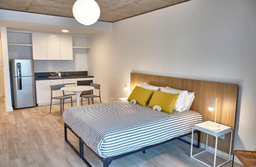 1 dormitorio con 1 cama con almohadas amarillas y cocina en Babel Botánico en Buenos Aires