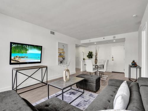 a living room with a couch and a tv on a wall at Gorgeous Miami Beach Condo Beach Service 1614 in Miami Beach