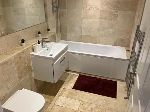 uma casa de banho com um lavatório, uma banheira e um WC. em Magnificent Refurbished 1 Bed Flat few steps to High St ! - 4 East House em Epsom