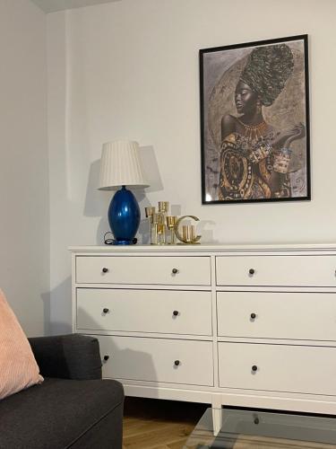 a bedroom with a white dresser with a picture on the wall at Apartament KaMaRo in Słubice