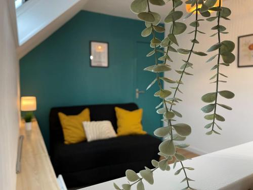 uma sala de estar com um sofá preto e uma planta em Évasion urbaine studio moderne à Chalon - BY PRIMO C0NCIERGERIE em Chalon-sur-Saône