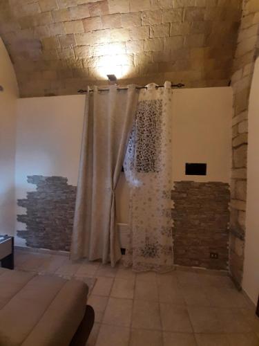 una tenda per la doccia in una stanza con muro di mattoni di La Dolce Volta a Tarquinia