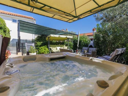 a hot tub in a backyard with an umbrella at Holiday Home Nena by Interhome in Buje