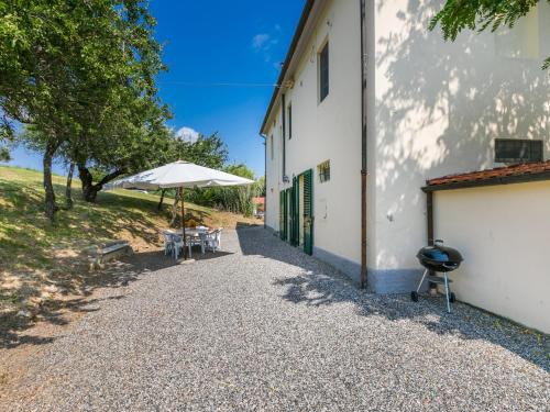 una mesa y una sombrilla junto a un edificio en Apartment Podere La Madonnina-3 by Interhome, en Nibbiaia