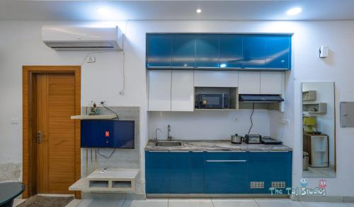 una cucina con armadi blu e piano di lavoro di LIMITLESSTRIP com- Best Stay at Central Noida #With Balcony #Free Parking #Wifi #Independent Apartment #Fully Equipped Kitchen a Noida