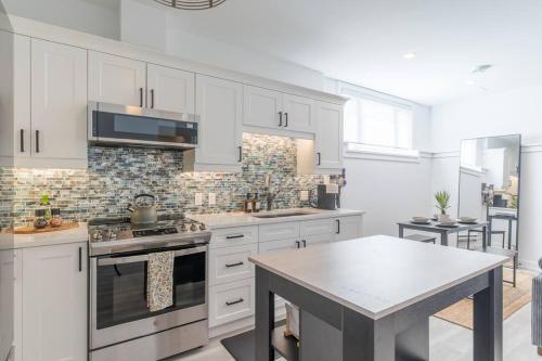 a kitchen with white cabinets and a table in it at Cozy Haven in Port Hope: Explore, Relax, Recharge in Port Hope