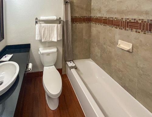 a bathroom with a toilet and a sink and a tub at Studio 6 Ontario CA Convention Center Airport in Ontario
