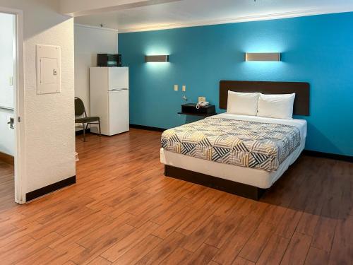 a bedroom with a bed and a blue wall at Studio 6 Ontario CA Convention Center Airport in Ontario