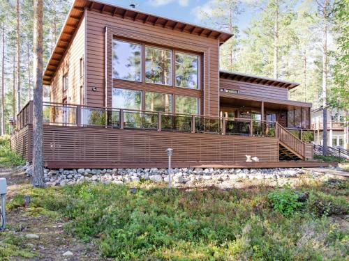 ein Blockhaus mit einer großen Terrasse im Wald in der Unterkunft Holiday Home Pielislinna-loma-koli by Interhome in Kolinkylä