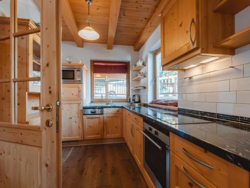 クリムルにあるHoliday Home Hochkrimml by Interhomeの大きなキッチン(木製キャビネット、カウンタートップ付)