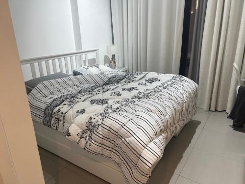 a bed with a black and white blanket on it at Sharjah Brand New Apartment in Sharjah