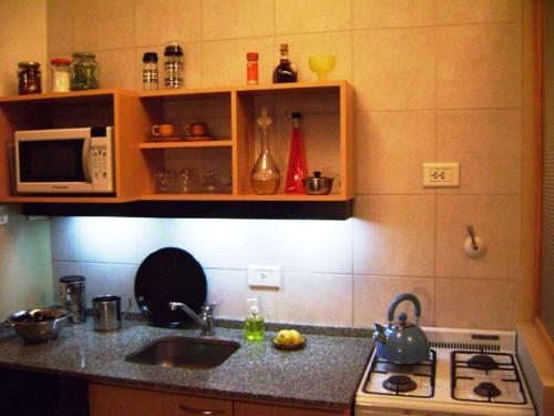 a kitchen with a stove and a sink and a microwave at Studio Rojo Belgrano in Buenos Aires