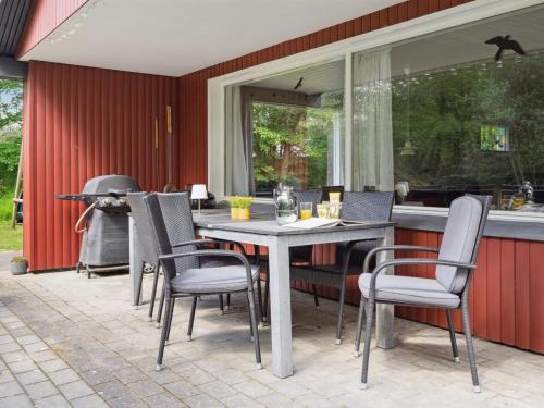 een patio met een tafel en stoelen en een grill bij Holiday Home Keyla - 3-2km from the sea in Western Jutland by Interhome in Rømø Kirkeby