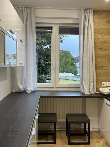 a kitchen with a counter with two stools and a window at Apartament KaMaRo in Słubice