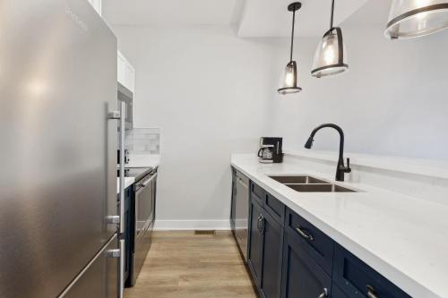 a kitchen with blue cabinets and a stainless steel refrigerator at 2 Bedroom Condo only steps to the Village! in Blue Mountains